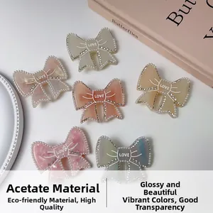 Detail of acetate bow hair clips with pearls, rhinestones and LOVE engraving on background