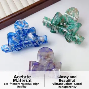 Macro detail of handmade acetate bow hair claws showing marble texture and vibrant colors