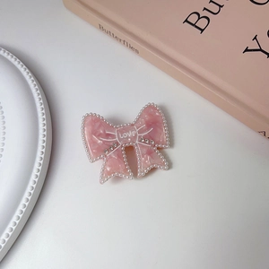 Macro detail of a pink acetate bow hair clip with faux pearls, rhinestones and LOVE text