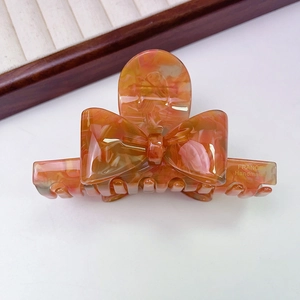 Close-up of orange amber pattern acetate bow hair claw clip with France Handmade gold text