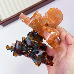 Detailed view of handmade acetate bow hair claws in marble pink and tortoise shell blue