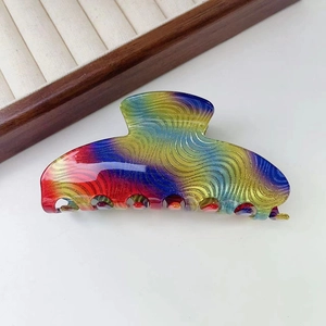 Macro shot of large rainbow gradient hair claw clip with wavy patterns and glossy finish