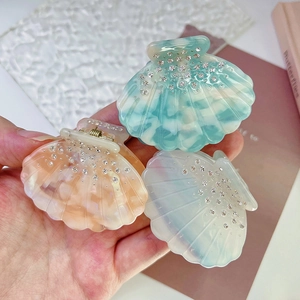 Detailed shot of shell-shaped acetate hair claws with rhinestones in pastel colors