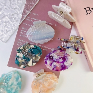 Iridescent shell-shaped acetate hair claws with sparkling rhinestones in various colors