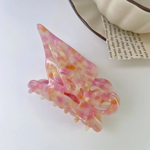 Close-up of pink marbled acetate butterfly hair claw with multi-tooth design in soft lighting