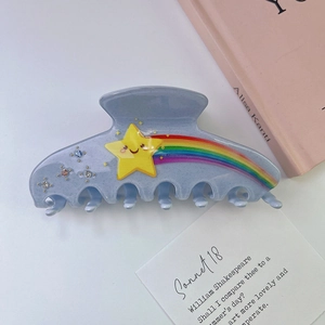 Détail de la pince à cheveux en acétate bleu clair avec motif étoile arc-en-ciel et strass