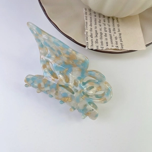 Detail of butterfly claw clip with blue and gold marble checkerboard pattern acetate