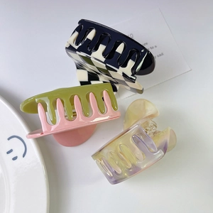 Close-up of checkerboard and colorful acetate hair claw clips on a minimalist ceramic plate