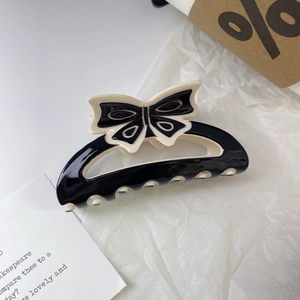 Détail d'une pince à cheveux noire avec nœud et bordure crème au style rétro élégant