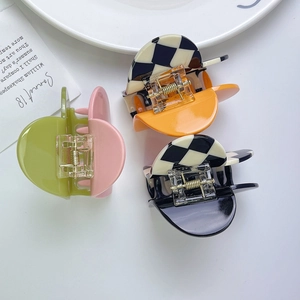 Detailed view of heart-shaped checkerboard hair claws in orange, green, and black acetate