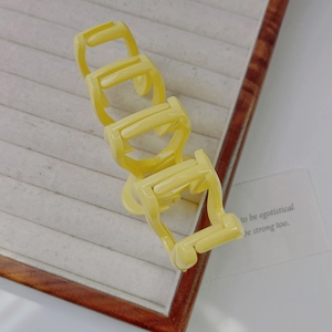 Detailed view of four yellow wavy hair claws neatly arranged on a velvet jewelry tray