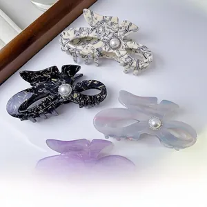 Close-up of bow-shaped acetate hair claws with pearls and cutout wings design