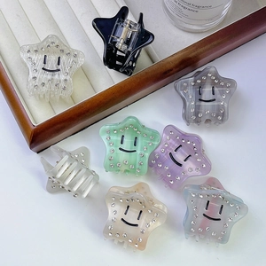 Close-up of star-shaped acetate hair claws with smiley face and sparkling rhinestones