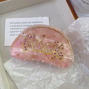 Detail view of pink acetate hair claw clip with crystal rhinestones and letter decor