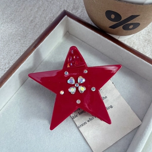 Dettaglio della pinza per capelli rossa a stella con fiori di cristallo a cuore