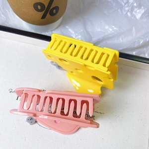 Detailed view of yellow cheese claw clip and pink hair clip on a white decorative tray