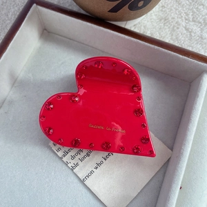 Dettaglio macro della molletta a cuore rosso con strass e logo dorato Barette La France