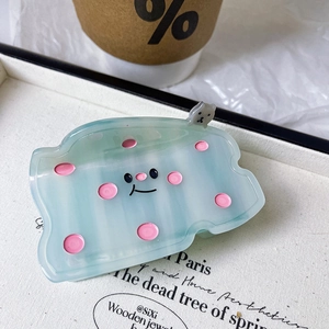 Detail of a light green translucent hair claw clip with pink polka dots and a cute bear