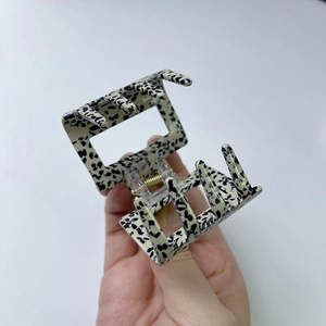 Close-up of a large cream acetate claw clip with black spotted pattern and gold spring detail