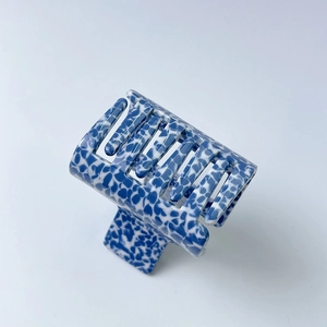 Detail of blue and white acetate hair claw clip with vintage stone pattern and smooth finish