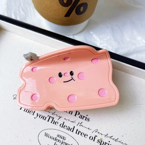 Detailed view of pink cheese hair claw with cute smiling face and small kitten charm