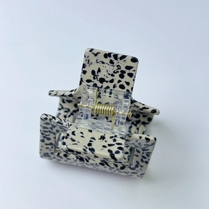 Detail of square hair claw clip with black and white spotted texture and golden spring