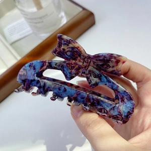 Detailed view of elegant violet and blue marbled bow hair claw clip in high-quality resin