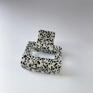 Minimalist marbled rectangular hair claw clip with black spots on cream white acetate base