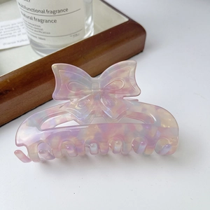 Detail of elegant bow hair claw clip with pink marble texture and pearlescent finish