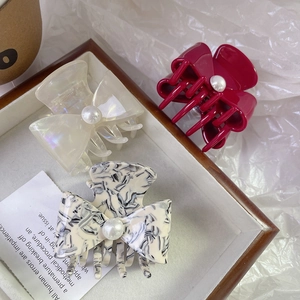 Elegant bow hair claws with pearls in white, dark red, and marble acetate patterns