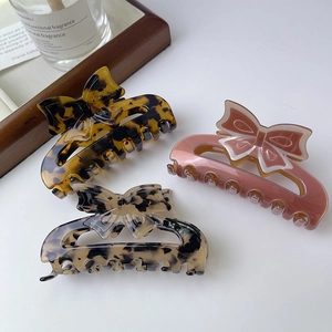Elegant bow hair claw clips set in tortoiseshell, matte pink, and marble patterns