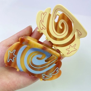 Détails rapprochés des pinces à cheveux en acétate avec motifs en spirale et étoiles