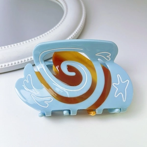 Close-up of a light blue acetate hair claw clip with heart and star patterns