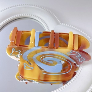 Detailed view of acetic acid hair claw with amber marble texture and blue star patterns