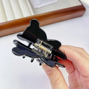 Detailed macro view of black bear-shaped hair claw clip with pearl accents and metal spring