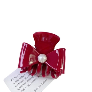 Elegant deep red bow hair claw clip with pearl accent on decorative paper base