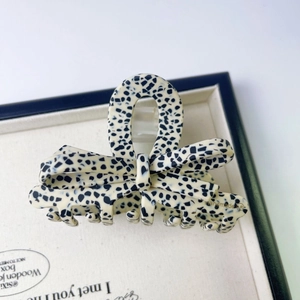 Détail d'une pince à cheveux faite main en acétate avec motif à pois noirs et blancs