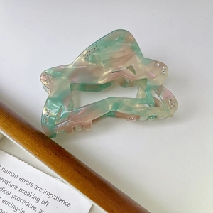 Detail of acetate shark hair claw with green marble texture and sparkling rhinestones