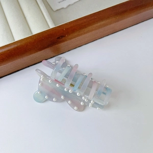 Close-up of a gradient pink and blue pearl hair claw clip on a jewelry organizer box
