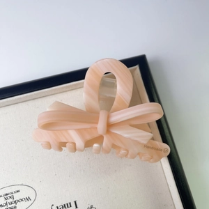 Détail d'une pince à cheveux à motif marbre rose avec logo fait main sur plateau en velours