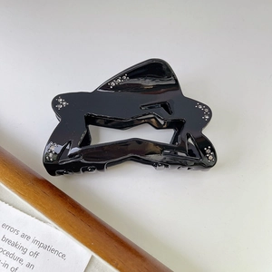 Close-up of black glossy hair claw clip with silver rhinestones on wavy geometric edges
