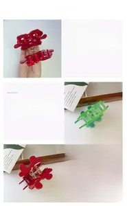 Detail view of red and translucent green acetate shark hair clips with wavy petal design
