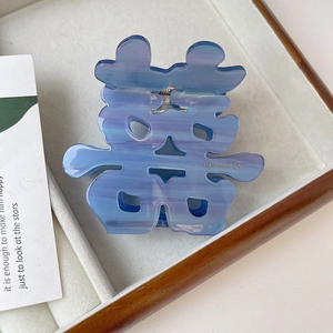 Detail of blue marble acetic acid hair claw with Chinese Xi character and gold handmade logo