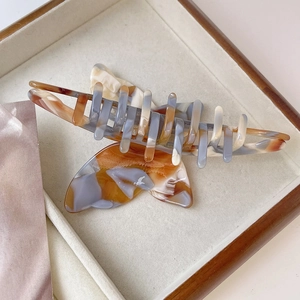 Detailed macro view of acetate butterfly hair claw with amber marble texture for thick hair