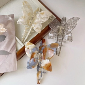 Three-piece set of butterfly acetate hair claws in marble white, grey, and amber tones