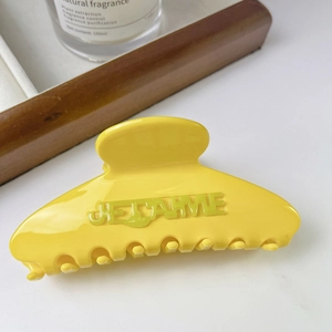 Vue macro d'une pince à cheveux en acétate jaune vif avec relief gravé JE T'AIME