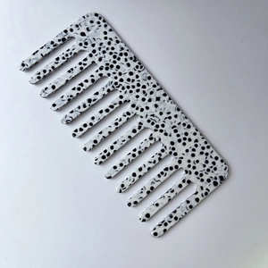 Detail of wide-tooth acetate hair comb featuring black and white dalmation spotted pattern