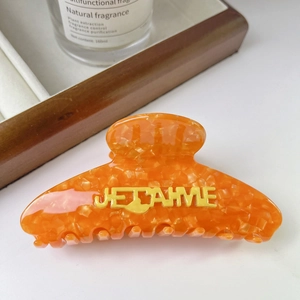 Détail de la pince à cheveux en acétate orange avec texte Je t'aime marbré