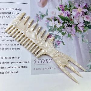 Detailed shot of cream marble acetate hair comb on a magazine background