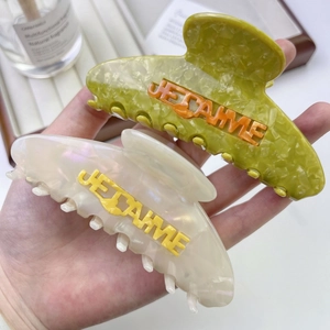 Gros plan de pinces à cheveux en acétate avec inscription 3D JE T'AIME tenue à la main